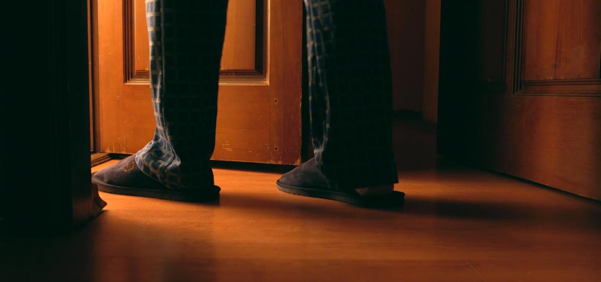 Man's legs and feet as he walks through door