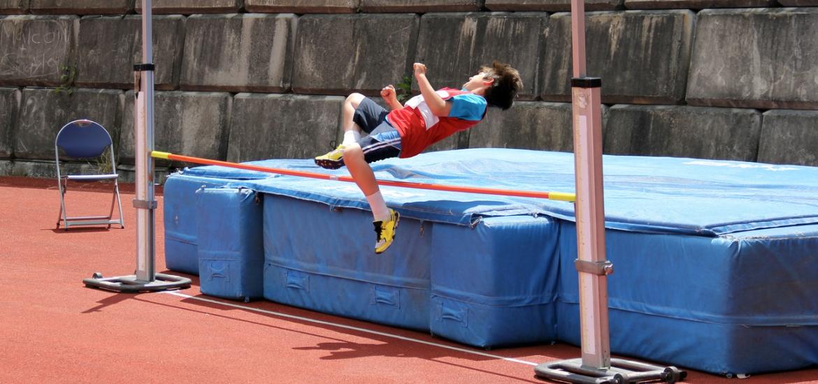 Boy jumping over high jump with bar set low