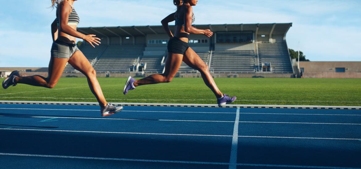 Two women racing on track, one in front of the other