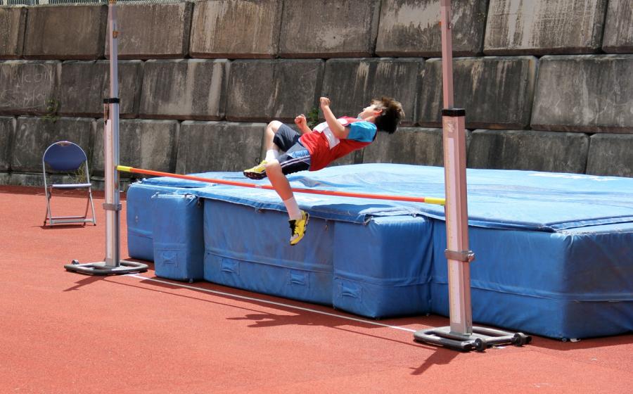 Boy jumping over high jump with bar set low