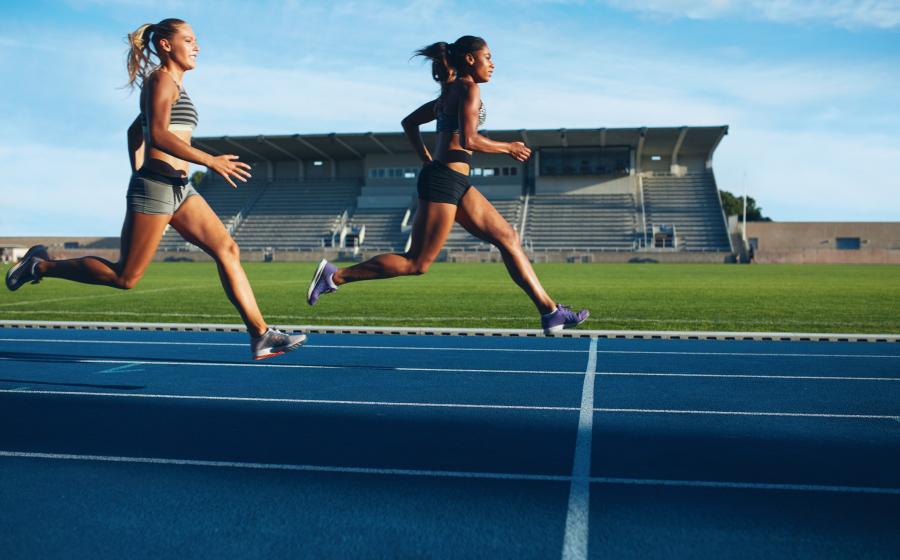 Two women racing on track, one in front of the other